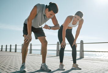 Tired couple, fitness and exercise time for performance or progress with blue sky at sea outdoor. Woman and man check watch mobile app in nature for workout, running and healthy lifestyle in summer