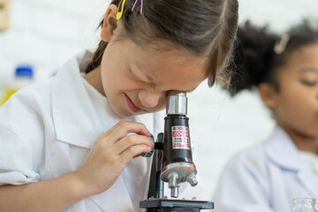 Lovely little girl scientist enjoy and excite to examine the color chemical in laboratory by using...