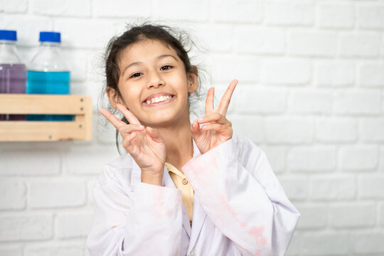 Lovely little girl scientist enjoy and excite to examine the color chemical in laboratory by using dropper with day light. Excited Kid celebrating over successful science experiment result or chemical