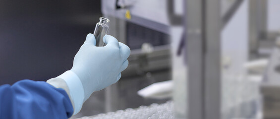 a hand in a medical latex glove holds a glass ampoule for vaccines Medical Glass vials Close-up