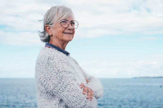 Portrait Of Pensive Handsome Senior Woman Standing By The Sea Looking Away. Smiling Elderly White-haired Lady In Outdoor Excursion Enjoying Freedom, Relax And Retirement