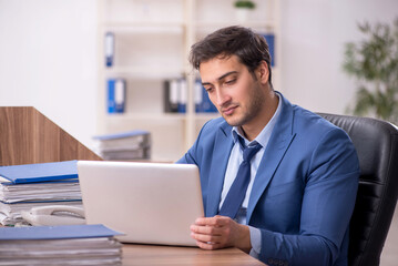 Young male employee and too much work in the office