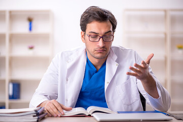 Young male doctor student reading book in the clinic