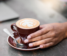 Latte cup, hands on table with art for customer services, restaurant creativity and hospitality industry with inspiration. Cafe shop with person hand holding espresso, cappuccino or coffee drink
