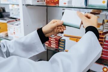 Closeup hand holding blank mockup pillbox from the shelf in pharmacy concept. Pharmacist or chemist...