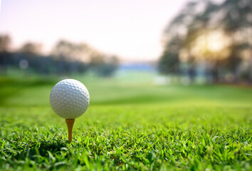 Close-up golf ball on tee with fairway golf course and morning light background.