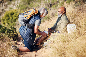 First aid, injury and knee pain with old men in nature for trekking, adventure and fitness. Help, bandage and medical with friends and leg accident on trail for backpacking, discovery and emergency