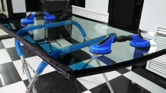 The windshield with suction cups in the service station lies on a stand before being installed in the car. Repair and installation of the windshield.