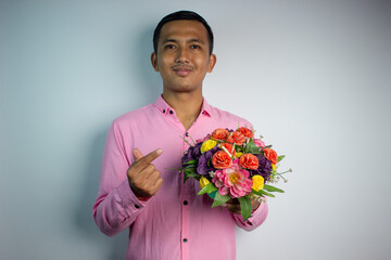 Portrait of Asian young man holding flower wearing pink shirt isolated on white background.