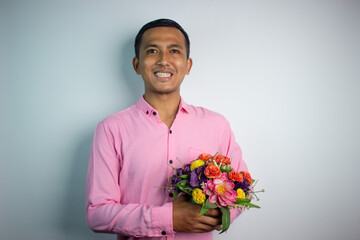 Portrait of Asian young man holding flower wearing pink shirt isolated on white background.