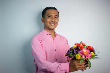 Portrait of Asian young man holding flower wearing pink shirt isolated on white background.