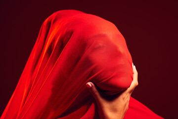 Model, red fabric and hidden face for fashion, aesthetic and beauty by dark studio background. Gen...