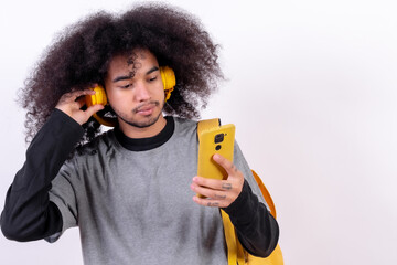 Young college boy with afro hair on white background, listening to streaming music online