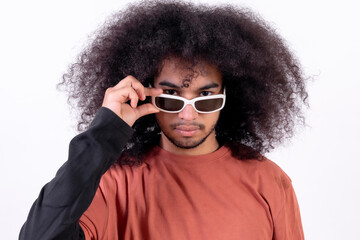 Portrait wearing sunglasses and looking at the camera. Young boy with afro hair on white background