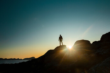 Man silhouette over a rock at sunset