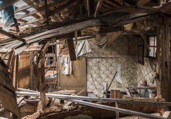Fototapeta na wymiar Urbex, destroyed room of an abandoned traditional South-Korean house, the walls, door and windows are broken, the roof collapsed, there are remains on the floor, the room is messy, dirty and dusty