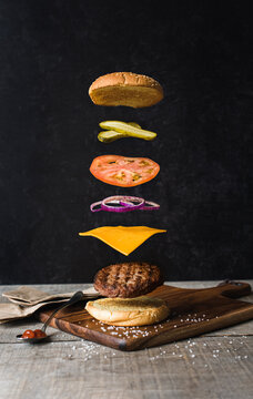 Burger with separated floating ingredients on black background.