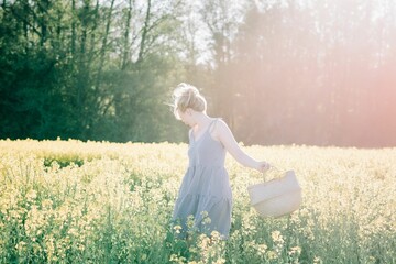 woman standing in a flower field with a basket picking flowers