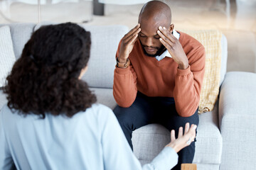Black man, mental health and counseling with woman psychologist, stress headache and depression...