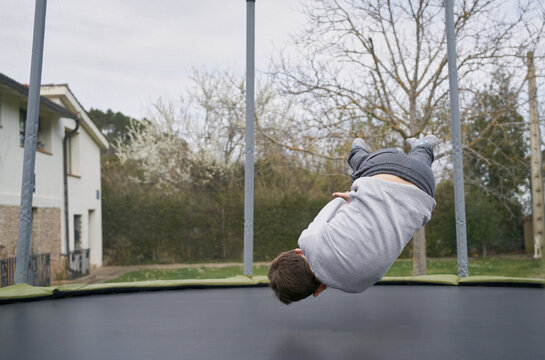 An Unrecognizable Guy Jumping Up And Down On A Trampoline