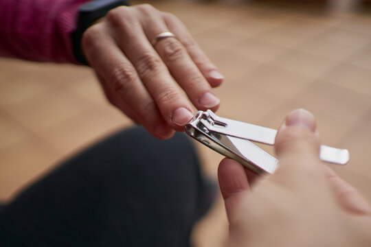 Anonymous person cutting nails with clipper