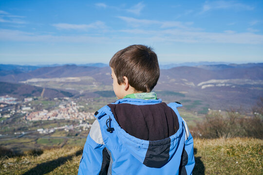 boy on his back looks at the landscape in autumn with a blue coat