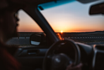 Sunrise through windshield of a car with a man driving