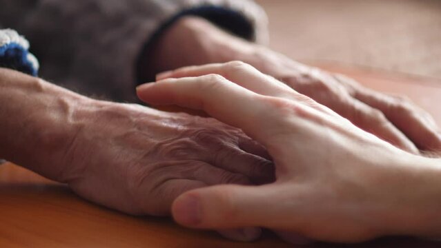 hands of an adult son and an elderly father embrace and friendship. son takes care of old parents. the concept of father's day, family relationships, love for the father, the son hugs the palm  father