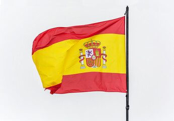 Spanish flag on the flagpole develops in the wind, light background