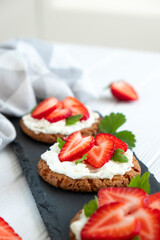 Healthy sandwich with strawberry and cream cheese on slate board. Tasty breakfast. Clean eating, diet or easy recipe of vegetarian sandwich for vegan menu.