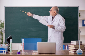 Old male teacher chemist sitting in the classroom