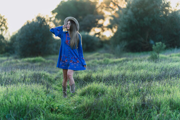 Chica joven con sombrero posando al atardecer en zona de campo