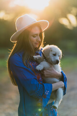 Chica joven con cachorro posando al atardecer en un bosque