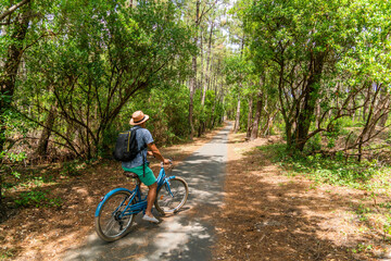 young mixed race black man on bicycle in forest trees vacation on a path in a natural holydays 