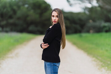 Fototapeta premium Chica joven con pelo largo liso y vestidos pintorescos en zona boscosa tomándose fotos y posando