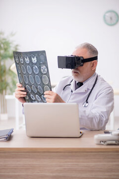 Old male doctor wearing virtual glasses in the clinic