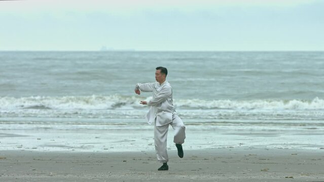 Kung-fu fighter training breathing technic on beach.