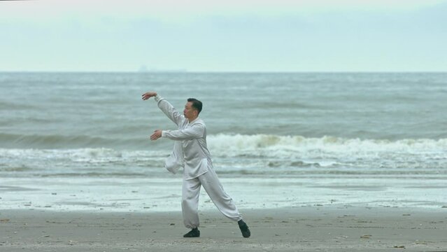Chinese kung-fu fighter training pose and breath on the beach.