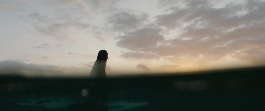 Surfer girl waiting the wave at sunset