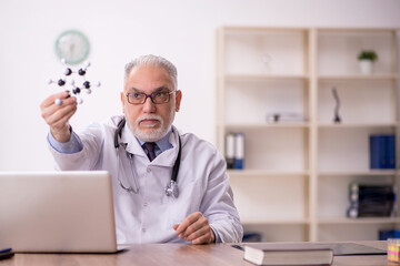 Old male doctor studying molecular model at the hospital
