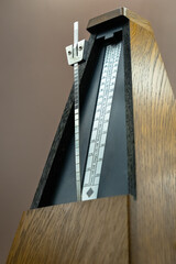 Old wooden metronome close up with brown background