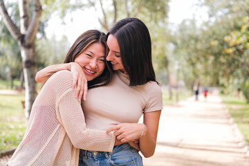 Fototapeta premium couple of happy women embracing and smiling during a date in a park, concept of friendship and love between people of the same sex