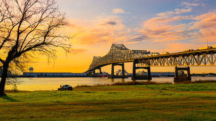 Horace Wilkinson Bridge over the Mississippi River green riverbank park with a barren willow tree...