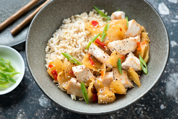 Middle close-up of chicken and kimchi stir-fry served with brown rice in a dark-olive bowl, horizontal shot, selective focus