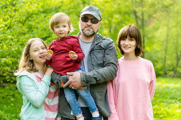 Young father and his three kids hiking in the woods. Family of four having fun on a walking trail on sunny spring day.
