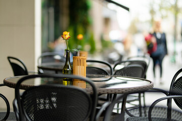 Outdoor restaurant table beautifully decorated with rose flower in a bottle in Vilnius, Lithuania, on nice summer day.