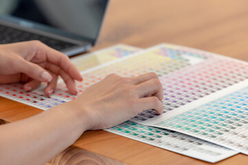 Close up, Woman's hands chosen color shades samples. Female interior designer working with color guide samples. Color swatches book, selecting color samples for interior design project.