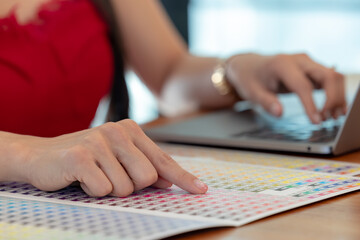 Close up, Woman's hands chosen color shades samples. Female interior designer working with color guide samples. Color swatches book, selecting color samples for interior design project.