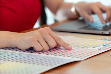 Close up, Woman's hands chosen color shades samples. Female interior designer working with color guide samples. Color swatches book, selecting color samples for interior design project.