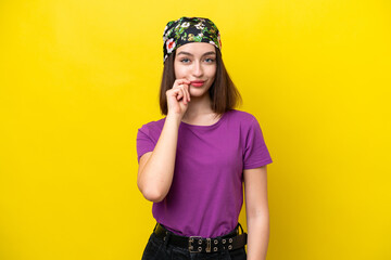Young Ukrainian woman isolated on yellow background showing a sign of silence gesture